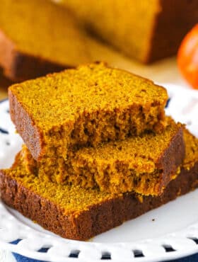 Two halves of Pumpkin Bread on top of another slice of Pumpkin Bread on a white plate
